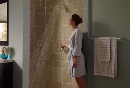 Woman standing in bath robe turning on shower