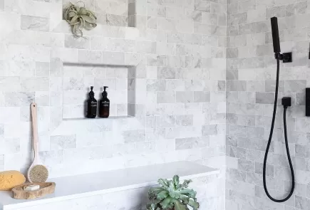 tiled shower with matte black hand shower and fixtures
